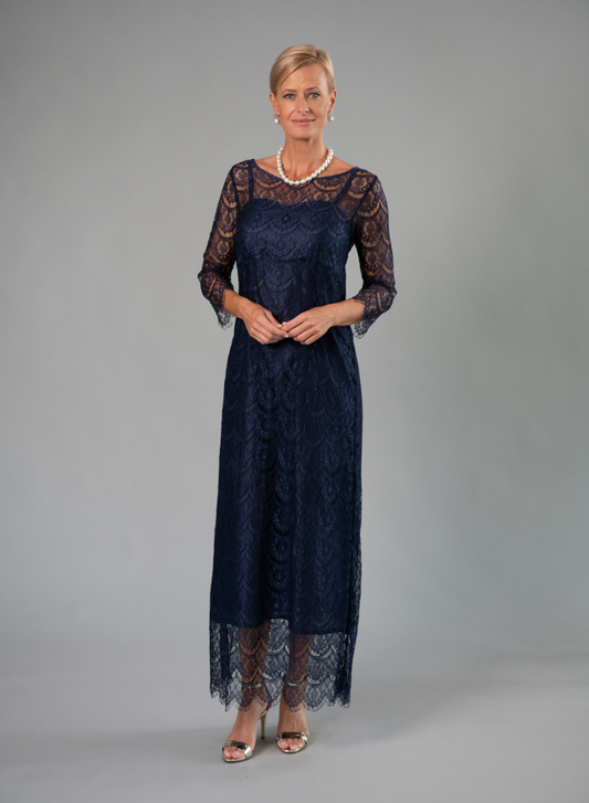Woman wearing a navy lace dress against a gray background
